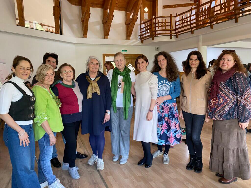 Grup de femei zâmbitoare într-o clădire din lemn.