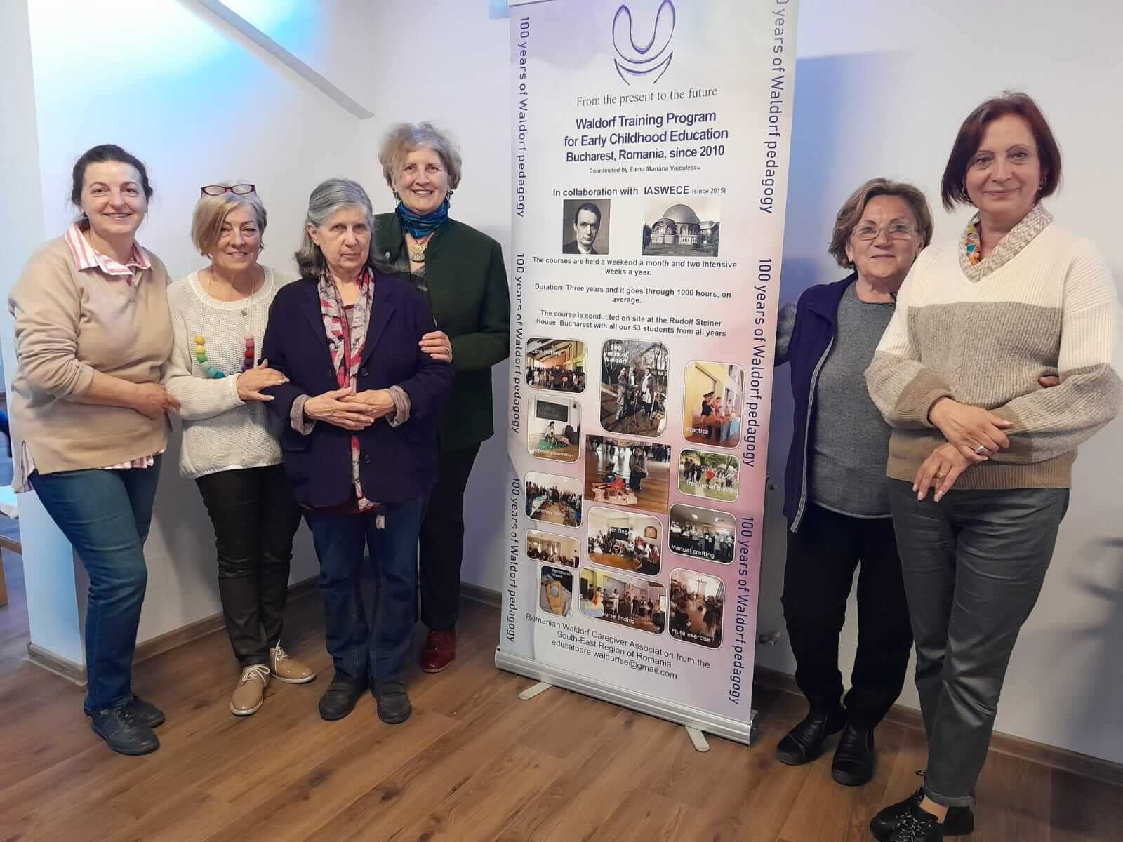 Grup de femei lângă afiș de educație Waldorf.